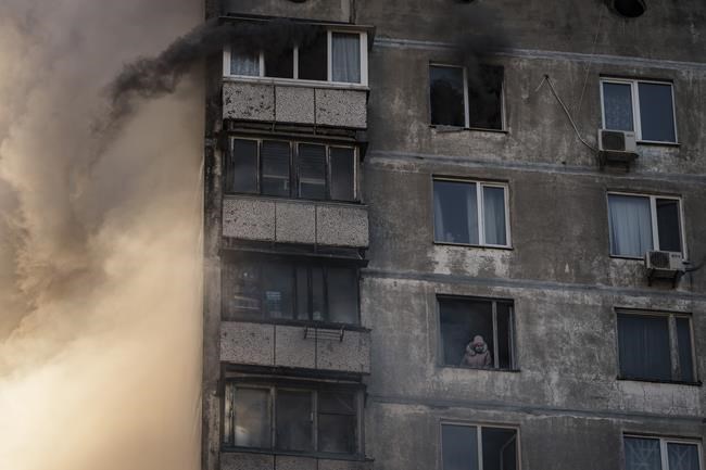 An elderly resident waits to be rescued by firefighters after the apartment building was hit by shelling in Kyiv, Ukraine, Tuesday, March 15, 2022. (AP Photo/Felipe Dana)