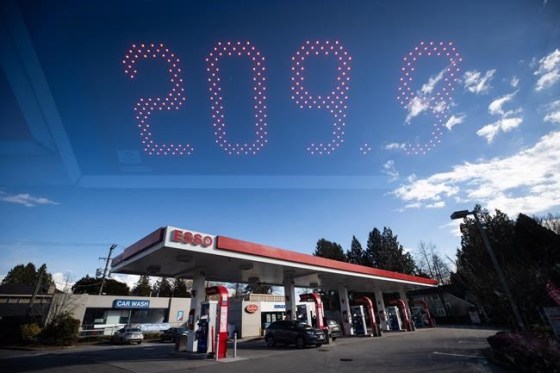 In this double exposure photograph, a sign displays the price of a litre of regular grade gasoline as people fuel up their vehicles at an Esso gas station, in Vancouver, on Tuesday, March 8, 2022. THE CANADIAN PRESS/Darryl Dyck