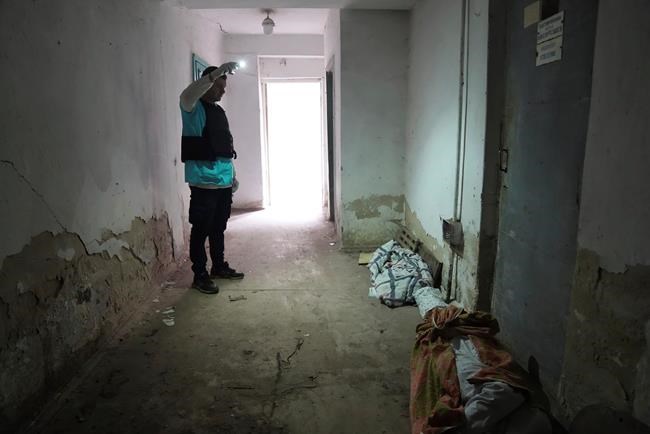 A police officer shows the covered bodies of people killed by shelling at hospital number 3 in Mariupol, Ukraine, Tuesday, March 15, 2022. (AP Photo/Evgeniy Maloletka)
