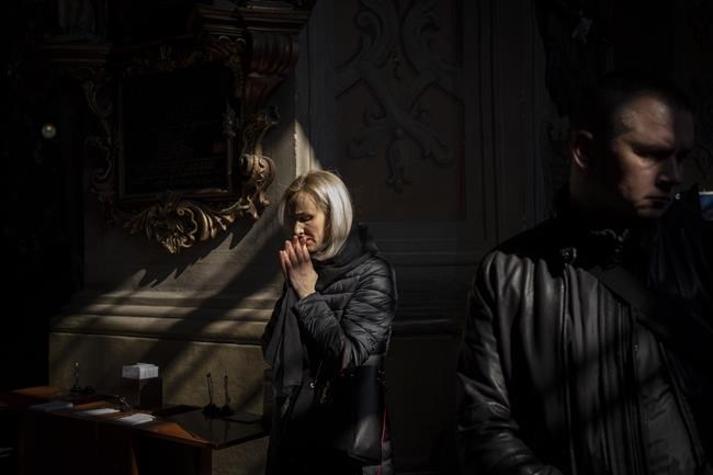 People attend a funeral ceremony for four of the Ukrainian military servicemen, who were killed during an airstrike in a military base in Yarokiv, in a church in Lviv, Ukraine, Tuesday, March 15, 2022. At least 35 people were killed and many wounded in Sunday's Russian missile strike on a military training base near Ukraine's western border with NATO member Poland. (AP Photo/Bernat Armangue)