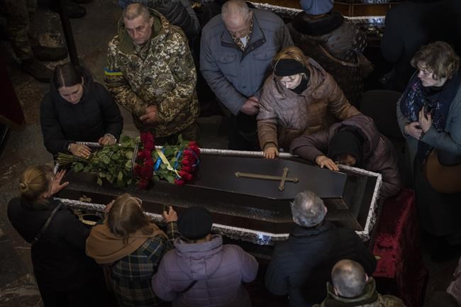 Relatives and friends attend a funeral ceremony for four of the Ukrainian military servicemen, who were killed during an airstrike in a military base in Yarokiv, in a church in Lviv, Ukraine, Tuesday, March 15, 2022. At least 35 people were killed and many wounded in Sunday's Russian missile strike on a military training base near Ukraine's western border with NATO member Poland. (AP Photo/Bernat Armangue)