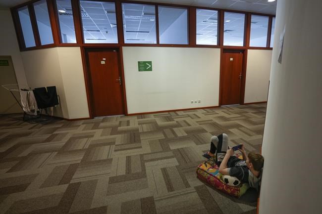 A Ukrainian child, who fled from war in Ukraine, holds a cellphone in a reception center, where he stays with others and their mothers in Warsaw, Poland, on Tuesday, March 15, 2022. As tens of thousands of Ukrainian children confront the trauma of becoming refugees in collective housing facilities hastily set up across central and eastern Europe, concerns are growing in the neighboring countries that have been greeting them with open arms about the monumental task of providing the new arrivals with long-term mental care and places in local schools. (AP Photo/Czarek Sokolowski)