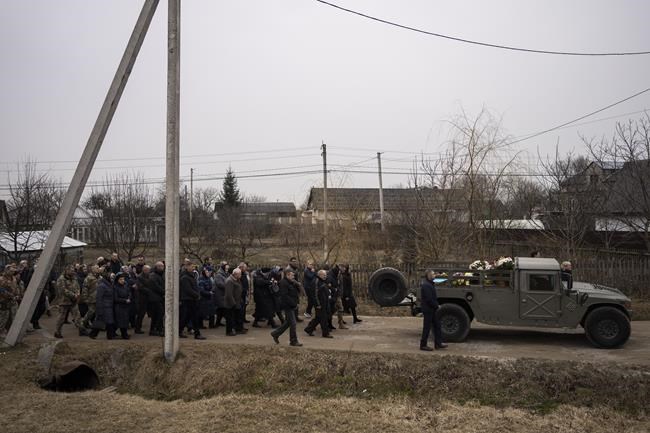 People attend a funeral ceremony for Ukrainian military servicemen Roman Rak and Mykola Mykytiuk in Starychi, western Ukraine, Wednesday, March 16, 2022. Rak and Mykytiu were killed during Sunday's Russian missile strike on a military training base in Yavoriv. (AP Photo/Bernat Armangue)