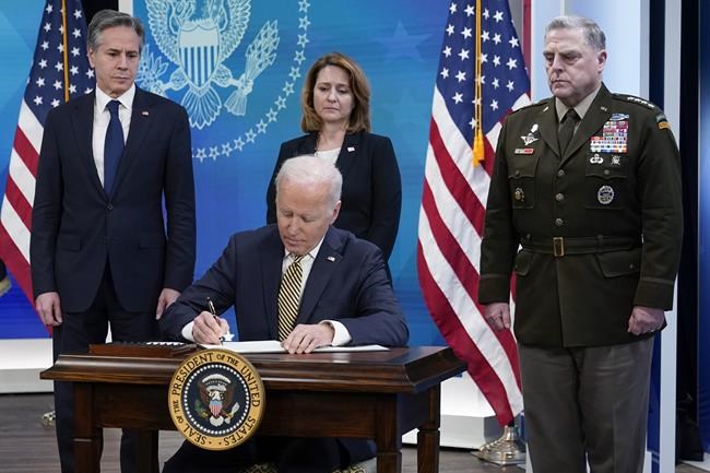 President Joe Biden signs a delegation of authority in the South Court Auditorium on the White House campus in Washington, Wednesday, March 16, 2022. From left, Secretary of State Antony Blinken, Biden, Deputy Secretary of Defense Kathleen Hicks and Chairman of the Joint Chiefs of Staff General Mark Milley. (AP Photo/Patrick Semansky)
