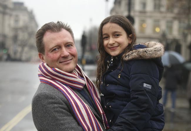 Richard Ratcliffe, left, poses for a photo with his daughter Gabriella, outside the Houses of Parliament in London, ahead of his wife Nazanin Zaghari-Ratcliffe's return, in London, Wednesday, March 16, 2022. Zaghari-Ratcliffe, a British charity worker who has been detained in Iran for almost six years, is flying home from Tehran after the U.K. government settled a decades-old debt to Iran. Zaghari-Ratcliffe and another dual national, Anoush Ashoori, who was detained in Tehran in 2017, boarded a plane from Tehran’s Mehrabad International Airport after the deal was struck. (James Manning/PA via AP)
