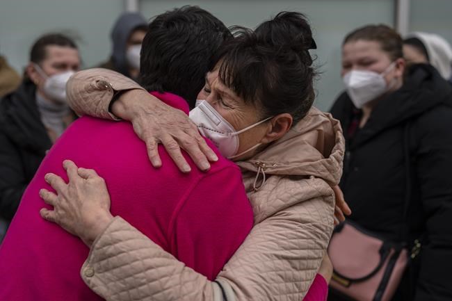 Displaced Ukrainians hug after arriving by bus at the Hospital Zendal in Madrid, Spain, Wednesday, March 16, 2022. (AP Photo/Manu Fernandez)