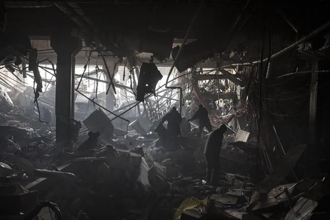 Ukrainian soldiers and firefighters search for people under debris inside a shopping center after shelling, in Kyiv, Ukraine, Monday, March 21, 2022. (AP Photo/Felipe Dana)