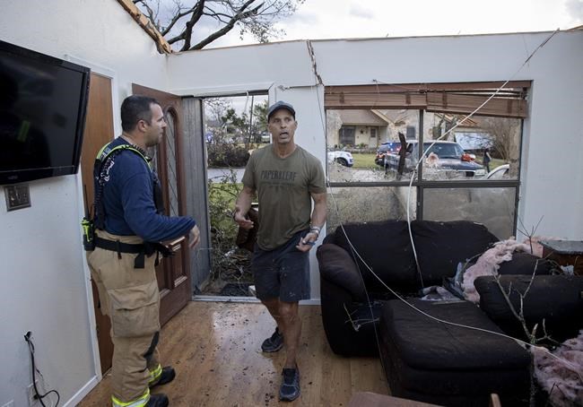 Michael Talamantez talks to a firefighter in his house on Stratford Drive in Round Rock, Texas, after it was destroyed by a tornado while he was inside on Monday March 21, 2022.