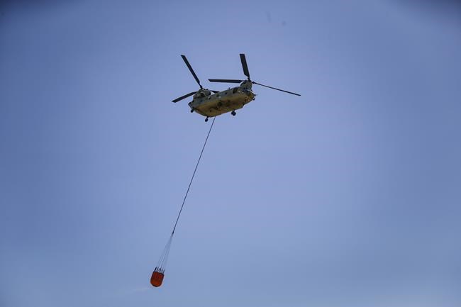 A helicopter flies toward smoke from wildfires, Sunday, March 20, 2022, near Eastland County in Texas. (Rebecca Slezak/The Dallas Morning News via AP)