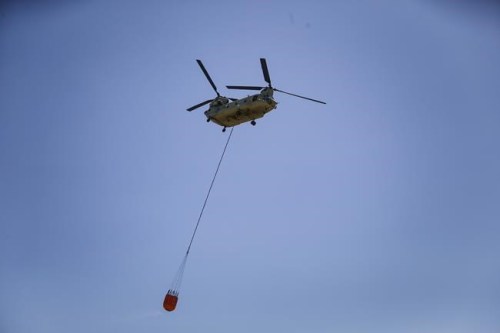 A helicopter flies toward smoke from wildfires, Sunday, March 20, 2022, near Eastland County in Texas. (Rebecca Slezak/The Dallas Morning News via AP)