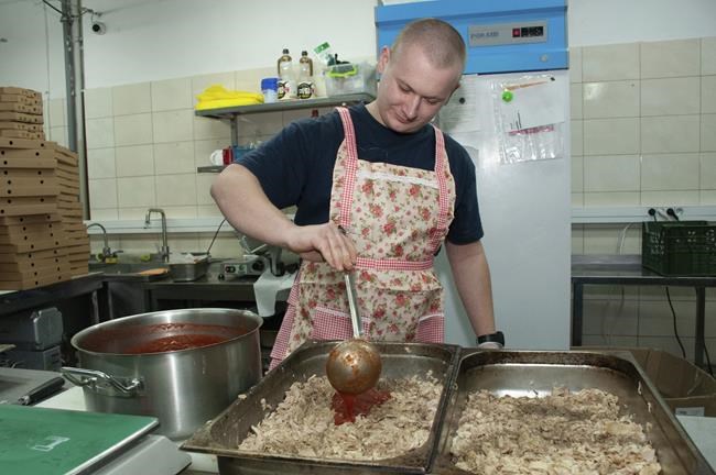A volunteer cooks food for Ukrainian servicemen in Kharkiv, Ukraine, Tuesday, March 22, 2022. (AP Photo/Andrew Marienko)