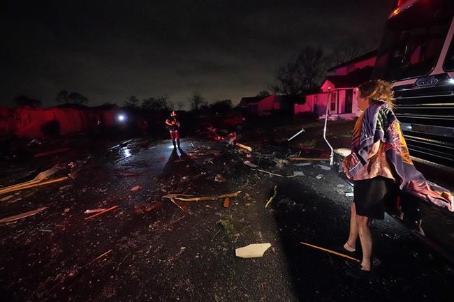 Melodie Maher watches from a fire truck as her son, Claude Maher, along with firefighters, rescued her dog from her heavily damaged home after a tornado struck the area in Arabi, La., Tuesday, March 22, 2022. A tornado tore through parts of New Orleans and its suburbs Tuesday night, ripping down power lines and scattering debris in a part of the city that had been heavily damaged by Hurricane Katrina 17 years ago. (AP Photo/Gerald Herbert)