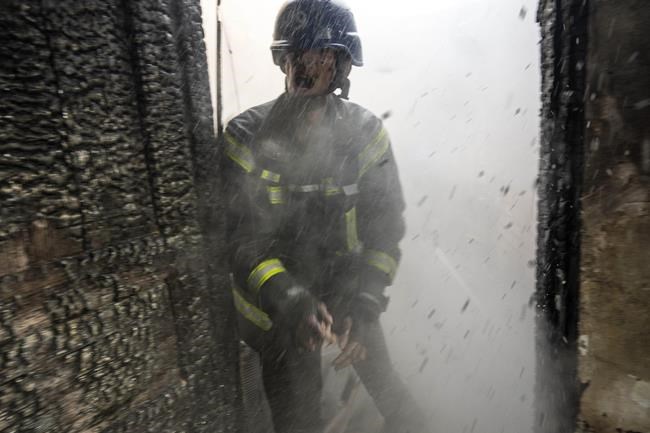 A Ukrainian firefighter shouts to a colleague while trying to extinguish a fire inside a house destroyed by shelling in Kyiv, Ukraine,Wednesday, March 23, 2022. The Kyiv city administration says Russian forces shelled the Ukrainian capital overnight and early Wednesday morning, in the districts of Sviatoshynskyi and Shevchenkivskyi, damaging buildings. (AP Photo/Rodrigo Abd)