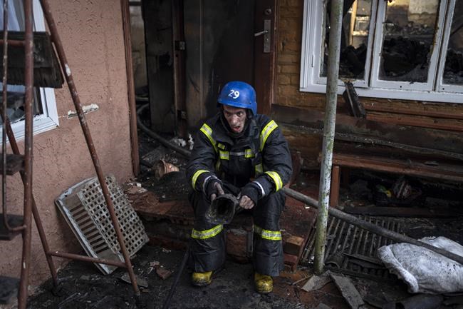 A Ukrainian firefighter takes a break from extinguishing a fire inside a house destroyed by shelling in Kyiv, Ukraine, Wednesday, March 23, 2022. The Kyiv city administration says Russian forces shelled the Ukrainian capital overnight and early Wednesday morning, in the districts of Sviatoshynskyi and Shevchenkivskyi, damaging buildings. (AP Photo/Rodrigo Abd)