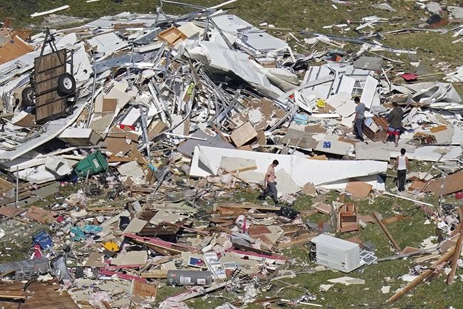 People walk amidst destruction from a tornado that struck on Tuesday night in Arabi, La., Wednesday, March 23, 2022. (AP Photo/Gerald Herbert)