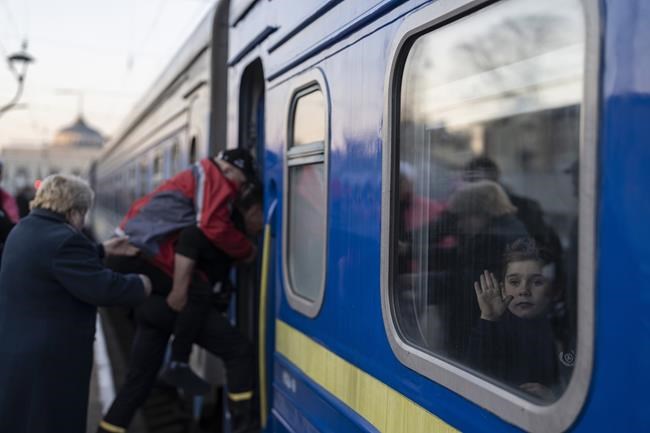 A man helps a disable elderly Ukrainian to embark a train as a children waves at the train station in Odesa, southern Ukraine, on Wednesday, March 23, 2022. The United Nations says more than 3.5 million people — mainly women and children — have fled Ukraine in the four weeks since Russian tanks rolled across the border and Moscow began bombarding towns and cities. (AP Photo/Petros Giannakouris)