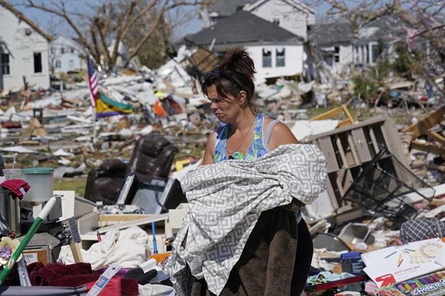 CORRECTS NAME OF HOMEOWNER TO JASON DICKENSON, NOT ERIC DICKERSON - Carrie Fontaine helps salvage belongings from her friend Jason Dickenson's home, Wednesday, March 23, 2022, in Arabi, La., after a tornado struck the area the night before. (AP Photo/Gerald Herbert
