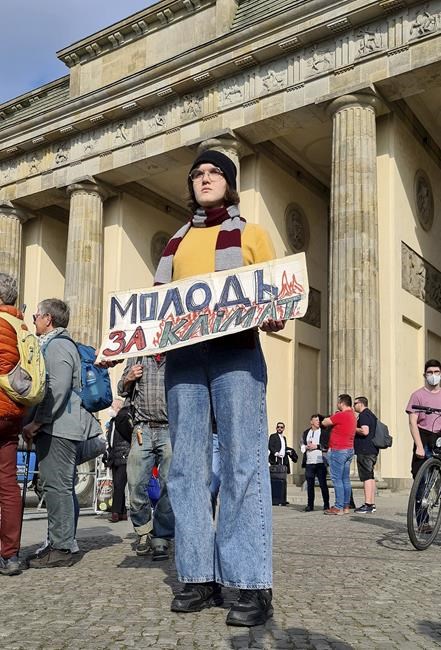 Ukrainian Ilyess El Kortbi holds a poster while taking part in a 'Fridays For Future' climate protest rally in front of the Brandenburg Gate in Berlin, Germany, Friday, March 25, 2022. Ukrainian slogan reads: 'Youth for Climate'. (AP Photo/Frank Jordans)