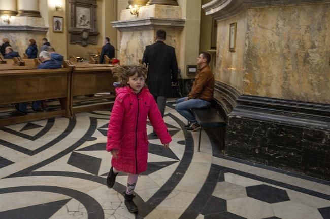 CORRECTS TO SERVICE, NOT MASS - A child runs during a service at the Holy Eucharist Church a day after Russian rockets hit an oil facility and factory in an industrial area, in Lviv, western Ukraine, Sunday, March 27, 2022. (AP Photo/Nariman El-Mofty)