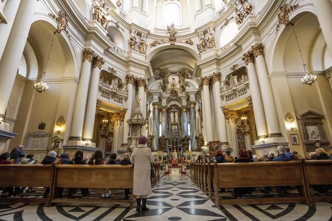 People pray during a service at the Holy Eucharist Church, a day after Russian rockets hit an oil facility and factory in an industrial area, in Lviv, western Ukraine, Sunday, March 27, 2022. (AP Photo/Nariman El-Mofty)