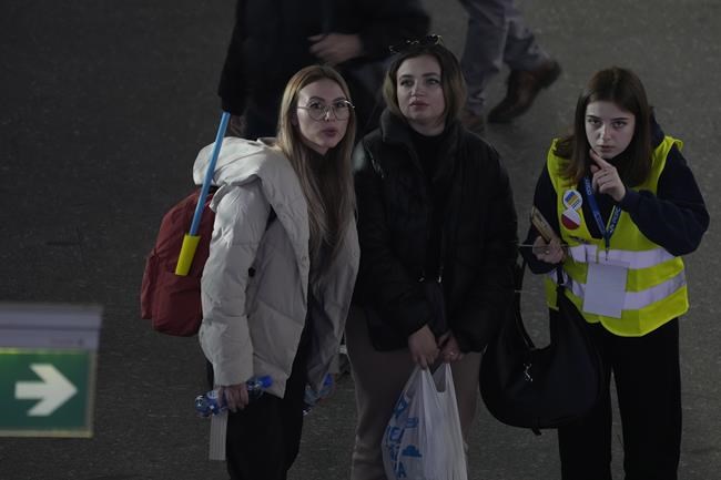 A Polish volunteer, right, directs two Ukrainian refugees at the central train station in Warsaw, Poland, Monday, March 28, 2022. The more than month-old war has killed thousands and driven more than 10 million Ukrainians from their homes — including almost 4 million from their country. (AP Photo/Czarek Sokolowski)