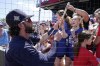 Atlanta Braves shortstop Dansby Swanson hands a souvenir back to a fan as he signs autographs prior to the start a spring training baseball game against the Toronto Blue Jays at CoolToday Park Monday March 28, 2022, in North Port, Fla. (AP Photo/Steve Helber)