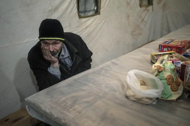 Borya, 58, evacuated from the town of Baryshivka by the Ukrainian government due to heavy fighting, waits inside a tent after arriving in Brovary, on the outskirts of Kyiv, Ukraine, Tuesday, March 29, 2022. (AP Photo/Rodrigo Abd)