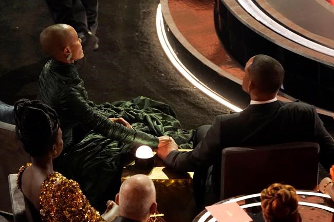 FILE - Jada Pinkett Smith, left, and Will Smith hold hands in the audience at the Oscars on March 27, 2022, at the Dolby Theatre in Los Angeles. The stunning physical altercation between actor Will Smith and comedian Chris Rock at the 94th Academy Awards on Sunday has sparked debate about the appropriate ways for Black men to publicly defend Black women against humiliation and abuse. (AP Photo/Chris Pizzello, File)
