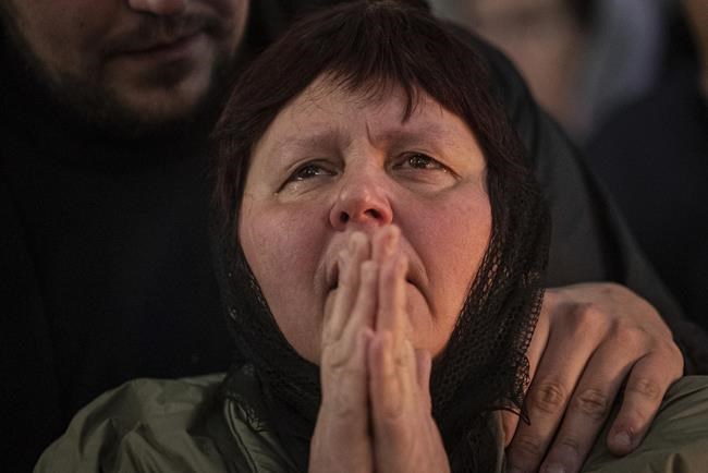 A relative of killed Ukrainian serviceman Georgiy Plisak reacts during funeral ceremony at an Orthodox Church in Lutsk, Ukraine, Thursday, March 31, 2022. Russian troops handed control of the Chernobyl nuclear power plant back to the Ukrainians and left the heavily contaminated site early Friday, more than a month after taking it over, Ukrainian authorities said, as fighting raged on the outskirts of Kyiv and other fronts. (AP Photo/Evgeniy Maloletka)
