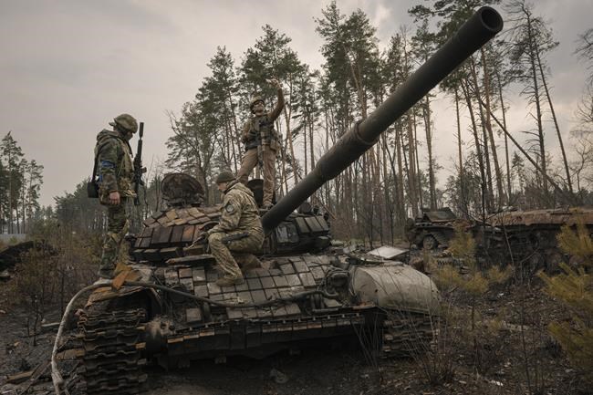 A Ukrainian serviceman takes a selfie photograph standing on a destroyed Russian tank after Ukrainian forces overran a Russian position outside Kyiv, Ukraine, Thursday, March 31, 2022. Heavy fighting raged on the outskirts of Kyiv and other zones Thursday amid indications the Kremlin is using talk of de-escalation as cover while regrouping and resupplying its forces and redeploying them for a stepped-up offensive in eastern Ukraine.(AP Photo/Vadim Ghirda)