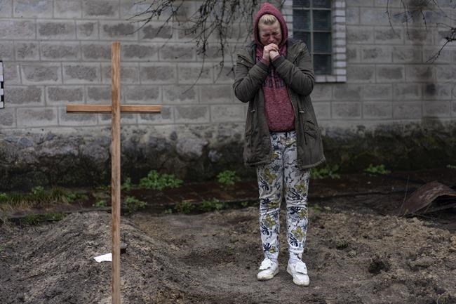 Mariya Ol'hovs'ka, 33, mourns the death of her father Valerii Ol'hovs'kyi, 72, killed by a Russian missile on March 30 near his house, on the outskirts of Kyiv, Ukraine, Friday, April 1, 2022. Maria and her family buried her father in the garden of their home as they could not bury him in the village cemetery due to fighting between the Ukrainian and Russian armies. (AP Photo/Rodrigo Abd)