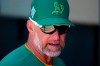 Oakland Athletics manager Mark Kotsay talks with coaches in the dugout prior to the team's spring training baseball game against the Colorado Rockies on Saturday, April 2, 2022, in Mesa, Ariz. (AP Photo/Ross D. Franklin)