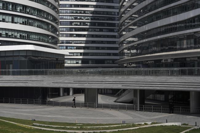 A security wearing a face mask to help protect from the coronavirus aligns the barricades at the Galaxy Soho commercial office building which was locked down for health monitoring following a COVID-19 case detected in the area, Tuesday, April 5, 2022, in Beijing. China has sent more than 10,000 health workers from across the country to Shanghai, including 2,000 military medical staff, as it struggles to stamp out a rapidly spreading COVID-19 outbreak in China's largest city. (AP Photo/Andy Wong)