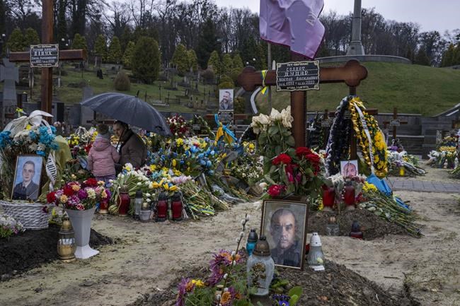 Tetiana Rurak, 25-year-old widow Oleksandra Rurak, visits her soldier husband Volodymyr Rurak's, grave with her one and a half year old daughter, after he was killed in action, at the Lychakiv cemetery, in Lviv, western Ukraine, Tuesday, April 5, 2022. (AP Photo/Nariman El-Mofty)