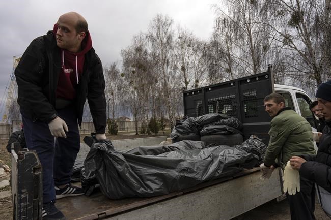 Cemetery workers receive three corpses of civilians killed in Bucha, before the corpses are transported to the morgue, on the outskirts of Kyiv, Ukraine, Wednesday, April 6, 2022. (AP Photo/Rodrigo Abd)