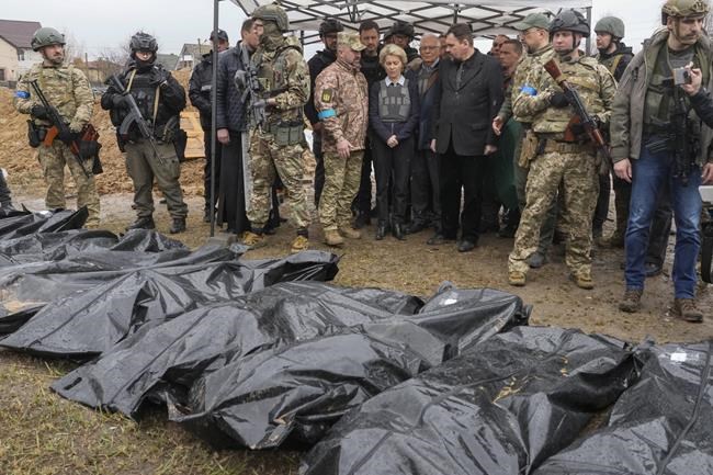 EU Commission President Ursula von der Leyen, center, looks at covered bodies of killed civilians in Bucha, on the outskirts of Kyiv, Ukraine, Friday, April 8, 2022. (AP Photo/Efrem Lukatsky)