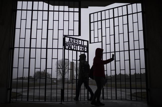 People take photos as they enter the Sachsenhausen Nazi death camp through the gate with the phrase 'Arbeit macht frei' (work sets you free), in Oranienburg, about 30 kilometres north of Berlin, Tuesday, Jan. 25, 2022. The Federal government is to use a bill enacting the budget to change the Criminal Code this year, building on existing laws outlawing the incitement of hatred. THE CANADIAN PRESS/AP-Markus Schreiber