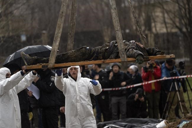 Forensic workers carry the corpse of a civilian killed during the war against Russia after collecting it from a mass grave in Kyiv, Ukraine, Friday, April 8, 2022. (AP Photo/Rodrigo Abd)
