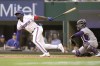 Texas Rangers Adolis Garcia, left, hits a two run RBI single in front of Colorado Rockies catcher Elias Diaz (35) during the fifth inning of a baseball ball game in Arlington, Texas, Monday, April 11, 2022. Texas Rangers Corey Seager and Charlie Culberson scored on the play. (AP Photo/LM Otero)