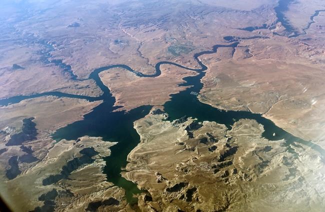 FILE - An aerial view of Lake Powell on the Colorado River along the Arizona-Utah border on Sept. 11, 2019. A dam holds back Lake Powell, one of the largest man-made reservoirs in the country. Federal officials sent seven western states a letter this week warning them that they're considering cutting the amount of water that flows through the Colorado River to the Southwest to maintain Lake Powell and prevent it from shrinking to a point at which Glen Canyon Dam could no longer produce hydropower. Consideration of what would be an unprecedented move comes sooner than water officials expected as they reckon with the effects drought and climate change have on their urban and agricultural customers. (AP Photo/John Antczak, FIle )