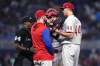 Philadelphia Phillies starting pitcher Kyle Gibson (44) talks with pitching coach Caleb Cotham, as home plate umpire Alan Porter arrives during the fourth inning of the team's baseball game against the Miami Marlins, Thursday, April 14, 2022, in Miami. (AP Photo/Lynne Sladky)
