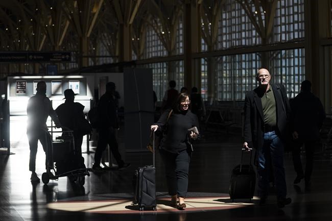 Passengers walk through the terminal at Ronald Reagan Washington National Airport, Tuesday, April 19, 2022, in Arlington, Va. A federal judge's decision to strike down a national mask mandate was met with cheers on some airplanes but also concern about whether it's really time to end the order sparked by the COVID-19 pandemic.(AP Photo/Evan Vucci)