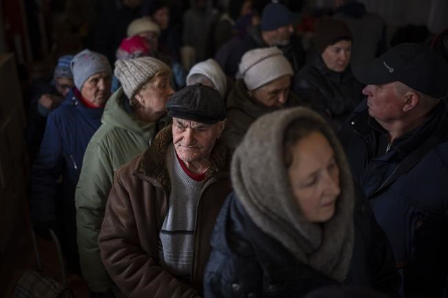 Ukrainians men queue inside a church to receive humanitarian aid donated by European Union in Bucha, on the outskirts of Kyiv, on Tuesday, April 19, 2022. Citizens of Bucha are still without electricity, water and gas after more than 44 days since the Russian invasion began. (AP Photo/Emilio Morenatti)
