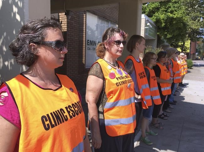 FILE - In this July 17, 2017, file photo, escort volunteers line up outside the EMW Women's Surgical Center in Louisville, Ky., the state's only abortion clinic. Frustration is building among abortion rights groups in Kentucky, where a restrictive new law has thrown the state’s only two remaining clinics into limbo. For women seeking abortions, it means traveling elsewhere or waiting for a judge to rule on requests to block the law. (AP Photo/Dylan Lovan, File)
