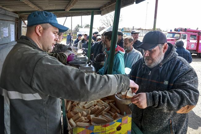 Local civilians line up to get a hot meals distributing by Donetsk People Republic Emergency Situations Ministry in an area controlled by Russian-backed separatist forces in Bezimenne village, eastern Ukraine, Wednesday, April 20, 2022. (AP Photo/Alexei Alexandrov)