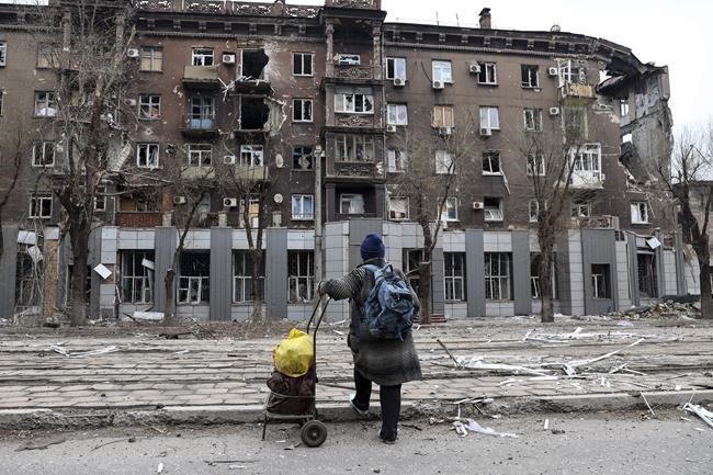 FILE - A local resident looks at a damaged during a heavy fighting apartment building near the Illich Iron & Steel Works Metallurgical Plant, the second largest metallurgical enterprise in Ukraine, in an area controlled by Russian-backed separatist forces in Mariupol, Ukraine, Saturday, April 16, 2022. Russian President Vladimir Putin ordered his forces not to storm the last remaining Ukrainian stronghold in the besieged city of Mariupol but to block it