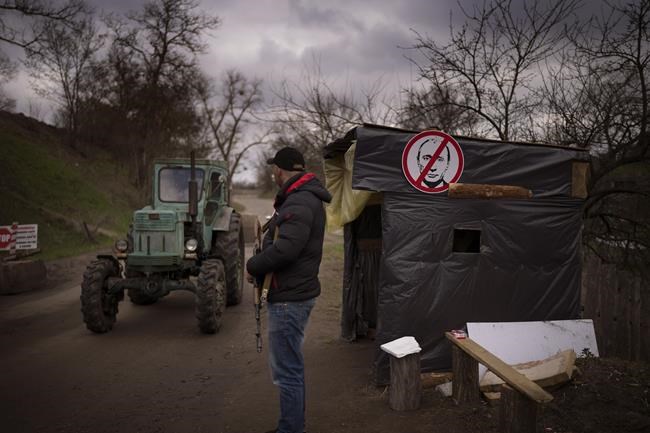 A civil defence volunteer stands guard at a checkpoint controlling the traffic near Kyiv, Ukraine on Thursday, April 21, 2022. (AP Photo/Emilio Morenatti)