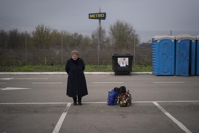 Helena stands next to her belongings after arriving from Mariupol at a refugee center in Zaporizhzhia, Ukraine, Thursday, April 21, 2022, after fleeing from the Russian attacks. Mariupol, which is part of the industrial region in eastern Ukraine known as the Donbas, has been a key Russian objective since the Feb. 24 invasion began. (AP Photo/Leo Correa)