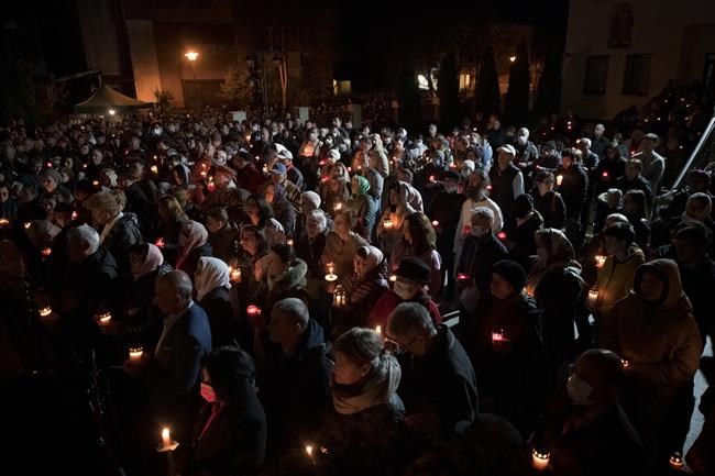 Orthodox worshipers hold candles during the Easter religious service at the Brancusi Parish Church in Bucharest, Romania, Sunday, April 24, 2022. The religious service was also attended by dozens of Ukrainian refugees living in a social center belonging to the church. (AP Photo/Andreea Alexandru)