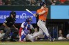 Houston Astros' Kyle Tucker comes around on his swing in front of Texas Rangers' Jonah Heim, center, on a double in the fifth inning of a baseball game, Wednesday, April 27, 2022, in Arlington, Texas. (AP Photo/Tony Gutierrez)
